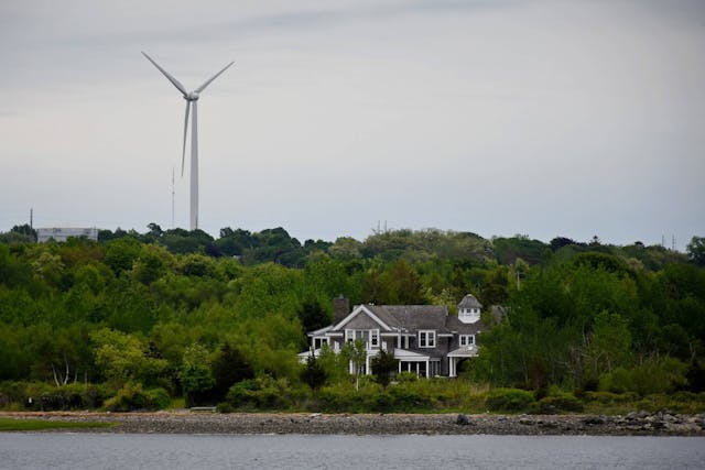 An onshore wind turbine visible in a coastal community in America. This image shows the coastal environment where Fugro works.