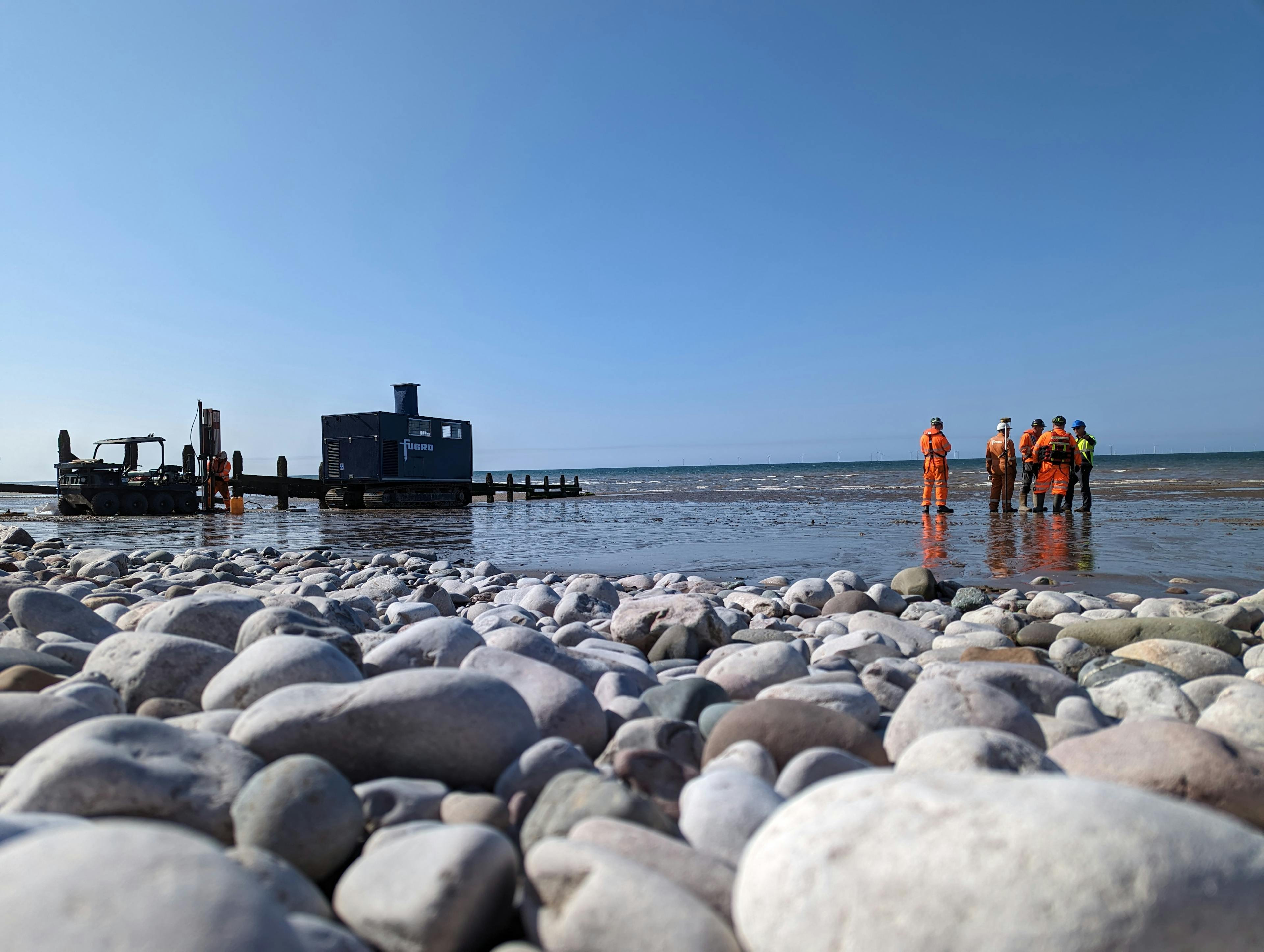 Deploying a CPT crawler from a landing barge to undertake a geotechnical ground survey on a beach for a wind farm cable landing.